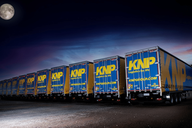 A row of KNP logistics trailers parked under a dark sky with a full moon , resized to a 1 6:9 aspect ratio and professionally enhanced. Filename : knp tra ilersmoon 16 9. png