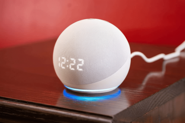 A white spherical Amazon Echo Dot with a clock display showing 12: 22 and a blue light ring at its base, sitting on a dark wooden surface against a red background .