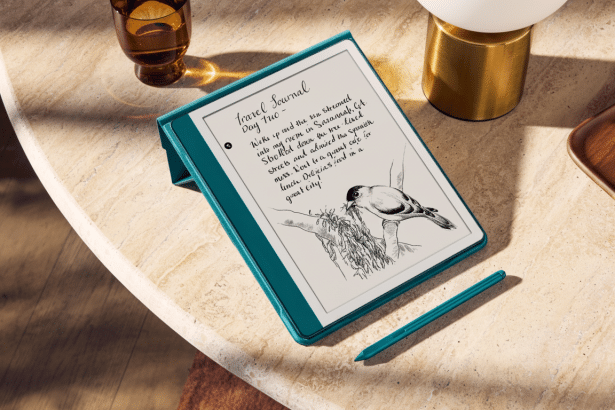 An e -reader with a teal cover showing a travel journal entry with a bird illustration, placed on a light marble table next to a glass, a golden lamp,