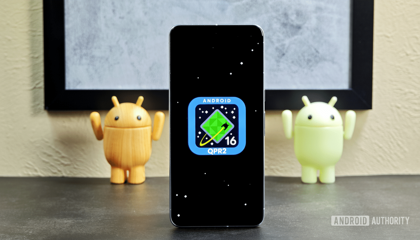 A smartphone displaying the Android 16 Q PR2 logo on a black screen, flanked by two Android figurines .