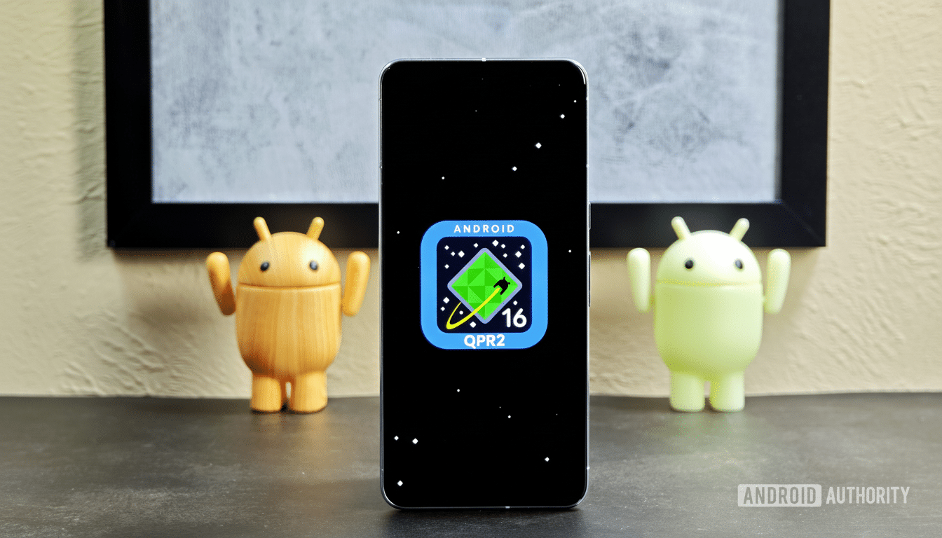 A smartphone displaying the Android 16 QPR 2 logo on its screen, flanked by two Android figurines , set against a background that includes a framed picture .