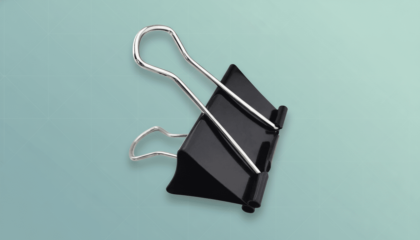 A black binder clip with silver handles on a light blue background with a subtle geometric pattern .