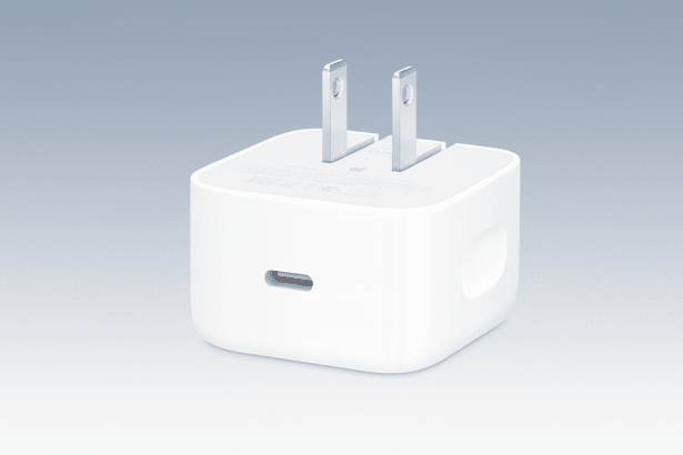 A white Apple USB -C power adapter on a professional flat gray background.