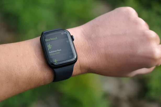 A close -up shot of a persons wrist wearing an Apple Watch, displaying the Workout app with Outdoor Run and Open Goal selected. The background is a na