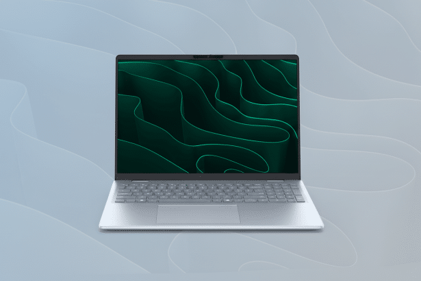 Text : A modern silver laptop with a dark green abstract wallpaper on its screen, placed on a light