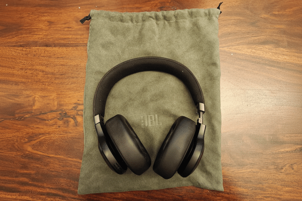 A pair of black JBL over -ear headphones resting on a green fabric pouch, all on a wooden surface.