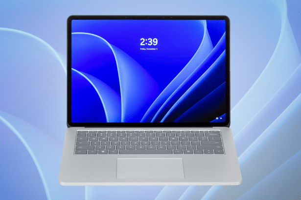 A modern silver laptop with a dark screen displaying 2: 39 Friday, November 5 against a blue abstract wallpaper. The background is a soft blue gradien