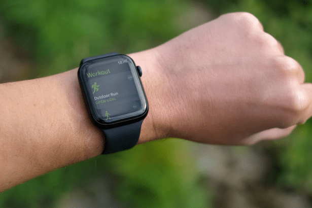 A close -up shot of a persons wrist wearing an Apple Watch, displaying the Workout app with Outdoor Run and Open Goal selected.