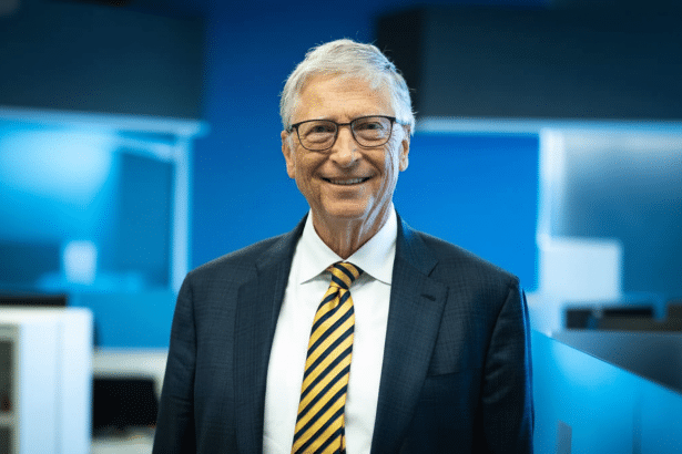 Bill Gates smiling in a professional setting, wearing a suit and a yellow and blue striped tie.