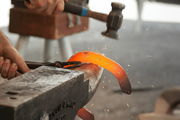 A blacksmith hammering a glowing hot horseshoe on an anvil , creating sparks.