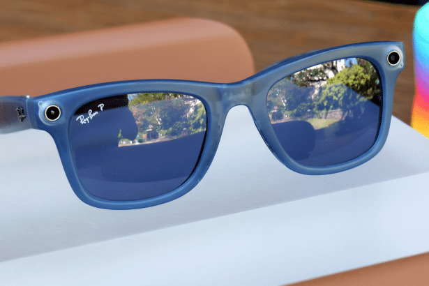 A pair of blue Ray-Ban smart glasses, seen from a slight angle, resting on a white surface with reflections of trees in the lenses.