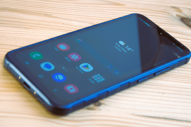 A blue smartphone with a screen displaying various app icons and a weather widget showing 14 degrees Celsius and partly cloudy in London, lying on a l