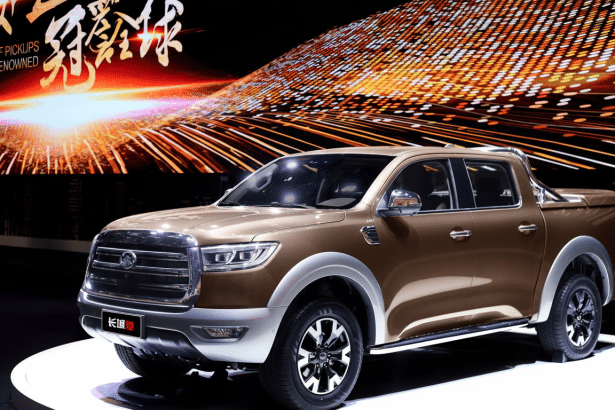 A professional shot of a brown pickup truck with silver accents , displayed on a circular white platform against a dynamic background of warm , stre aking lights and Chinese text. Filename : brownpickup truckdisplay .png