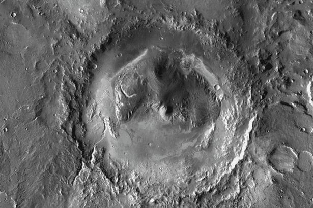 An aerial view of a large, circular impact crater on Mars, showing intricate geological formations and varying shades of gray and white .
