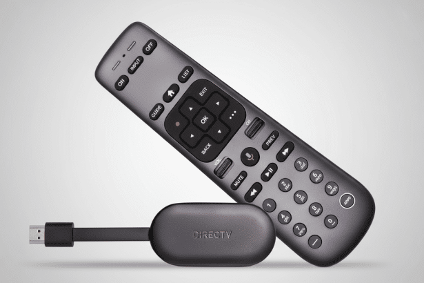 A dark gray DIRECT V streaming stick connected to a USB plug and a matching dark gray DIRECT V remote control. The background is a soft gradient from light gray to white .