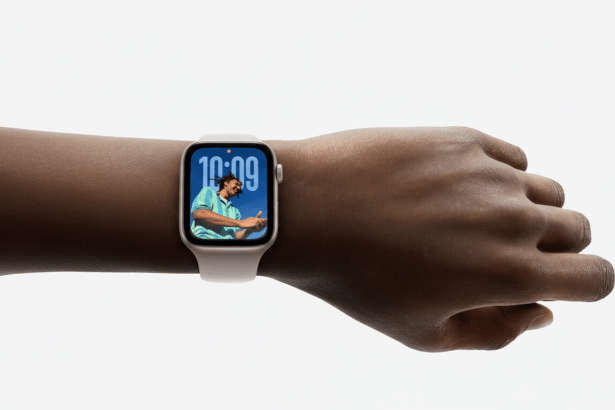 A close-up of a persons arm wearing a white Apple Watch Series 8 on a white background. The watch face displays the time 1 0: 09 and a colorful image