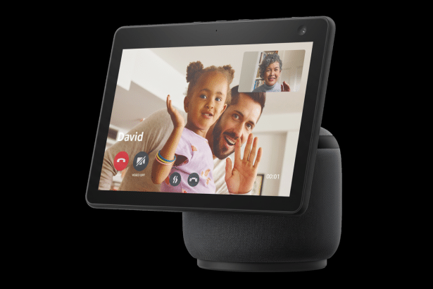 An Amazon Echo Show 1 0 displaying a video call with a man and a young girl waving, and a smaller inset of an older woman. The device is black with a