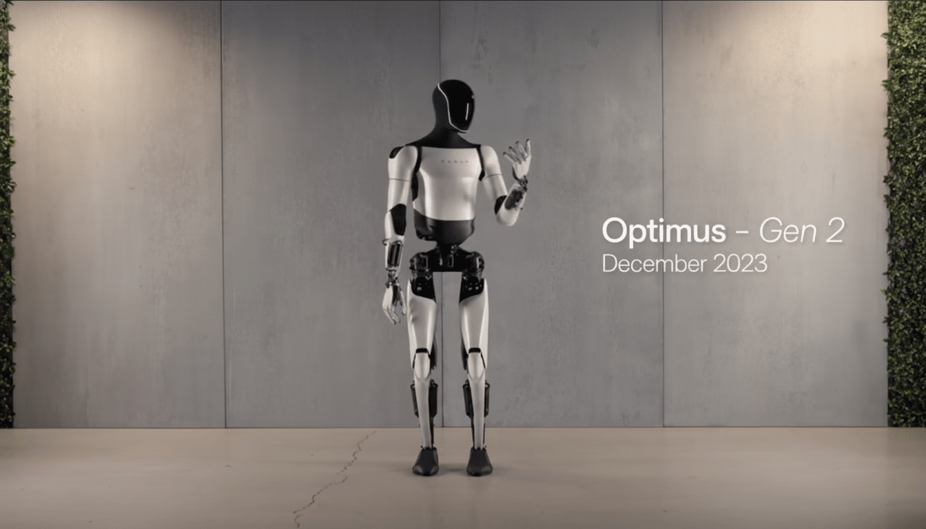 The Optim us Gen 2 humanoid robot in white and black, standing against a grey wall with a plant wall on the right.