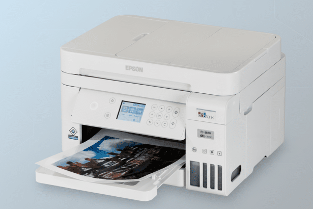 A white Epson ET-3 850 Eco Tank printer with a photo of a building printing, set against a professional light blue gradient background. Filename : epson et- 3850 ec otankprinter .png