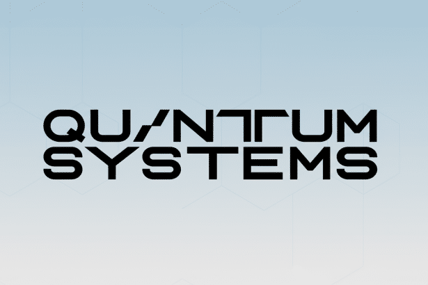The Quantum Systems logo, featuring stylized black text on a light blue and white gradient background with subtle hexagonal patterns, presented in a 1