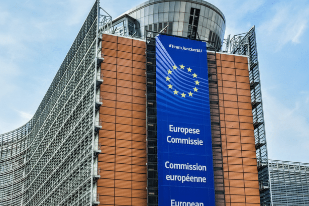 The European Commission building in Brussels, with a large blue banner displaying the European Union flag and the text #TeamJuncker EU, Eu ropese Comm