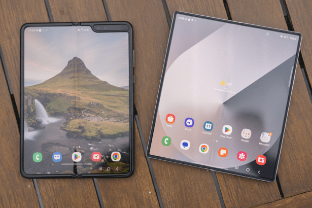 Two foldable smartphones displayed on a wooden surface, one open showing a landscape wallpaper with a mountain and waterfall, and the other displaying