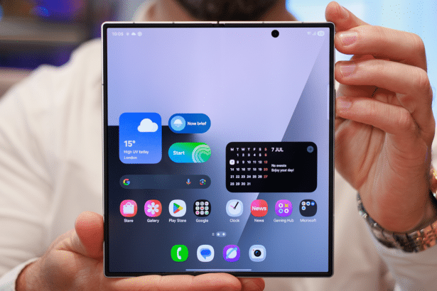 A person holding a foldable smartphone with various app icons and widgets displayed on its screen.