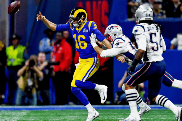 An American football player in a blue and yellow uniform , number 1 6, attempts to throw a football while being tackled by an opposing player in a white uniform .