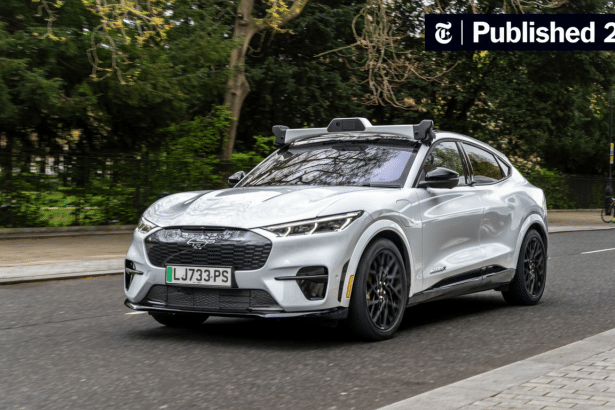 A white Ford Mustang Mach- E electric SUV driving on a road with trees in the background.