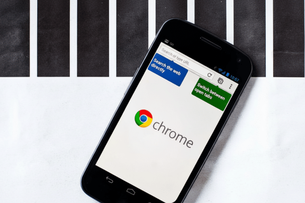 A black smartphone displaying the Google Chrome app interface, with the Chrome logo prominently featured on the screen. The phone is placed on a white