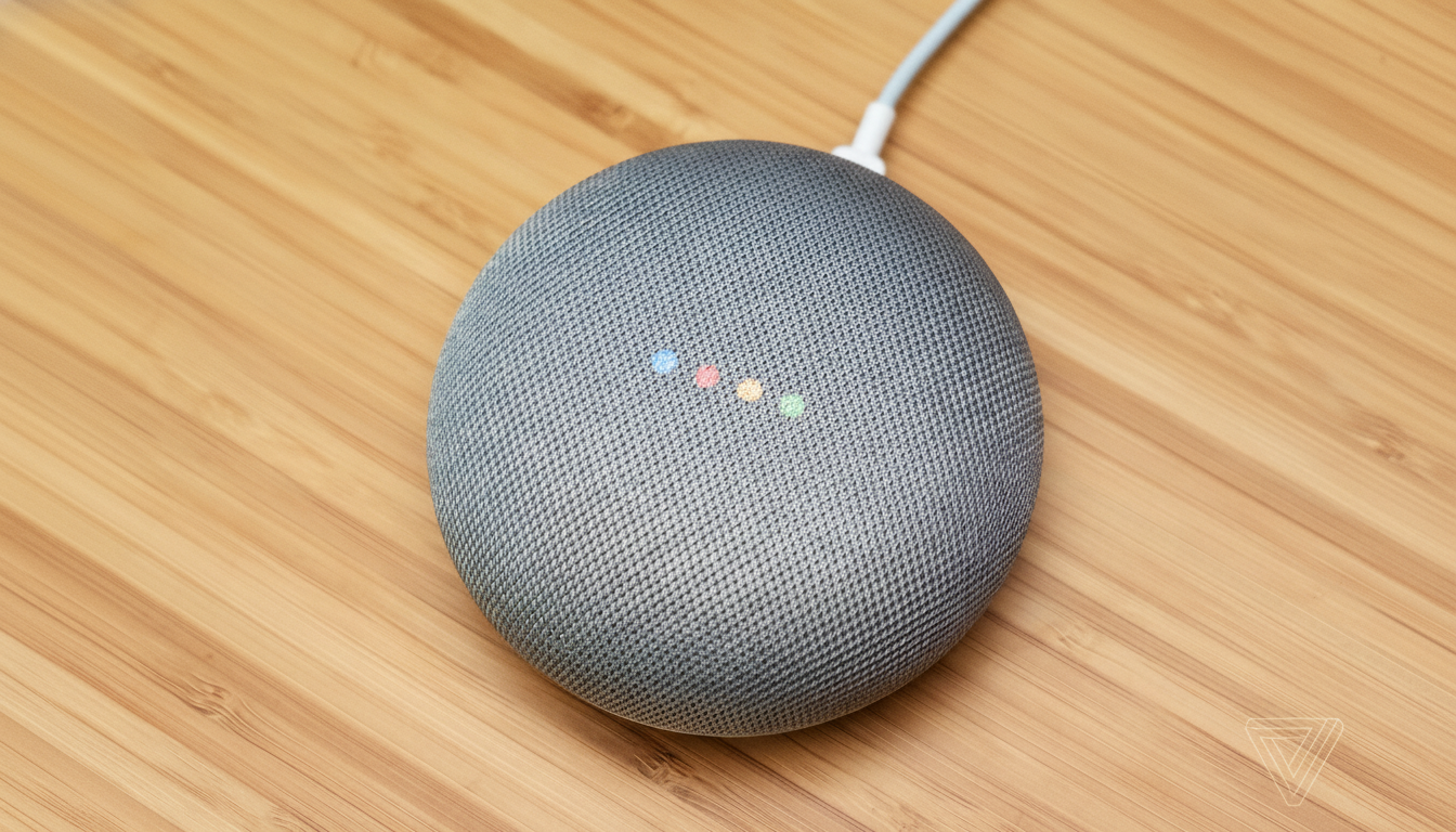 A gray Google Home Mini smart speaker with four colored indicator lights on its top surface, sitting on a wooden surface.