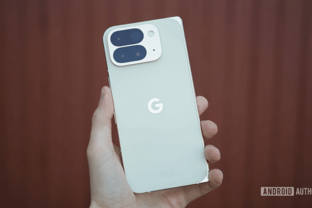 A hand holding a light green Google Pixel phone , showcasing its back design and camera module against a blurred reddish -brown background.