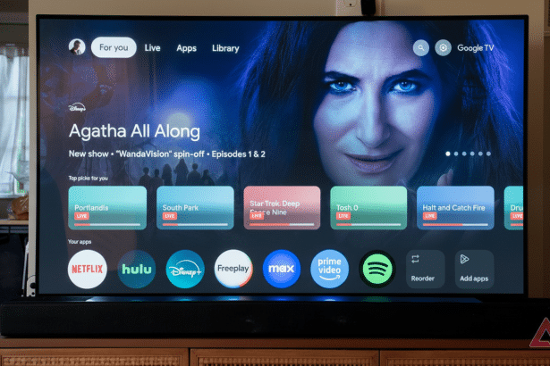 A smart TV displaying the Google TV interface with Agatha All Along highlighted , featuring Kathryn Hahn 's character from Wanda Vision. The screen shows various streaming apps like Netflix, Hulu , Disney+, and Prime Video. Filename : googletv interfaceag athaall along.png