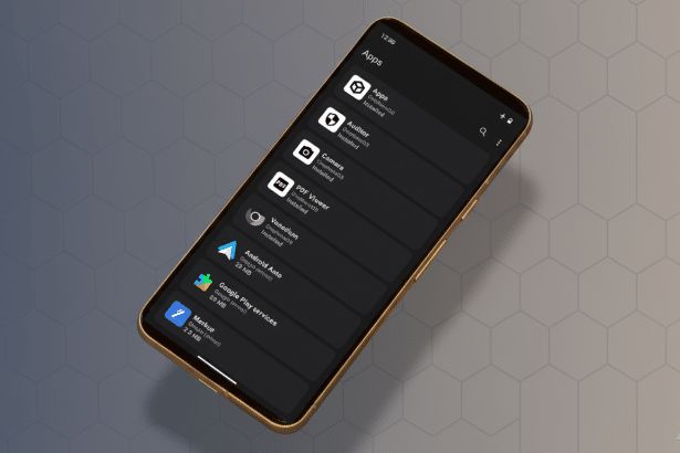 A gold-framed smartphone displaying an Apps screen with a list of applications like Auditor , Camera, PDF Viewer, and Android Auto, set against a professional, subtly patterned gray background. Filename : smartphone appsscreen . png