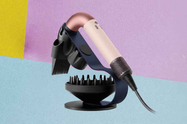 A professional shot of a modern hair dryer with multiple attachments, including a diffuser and a comb, on a stand . The hair dryer is rose gold and beige, with a dark blue strap securing it to the stand. The background is a soft gradient of purple , yellow, and blue. Filename : hairdry erprofessional display .png