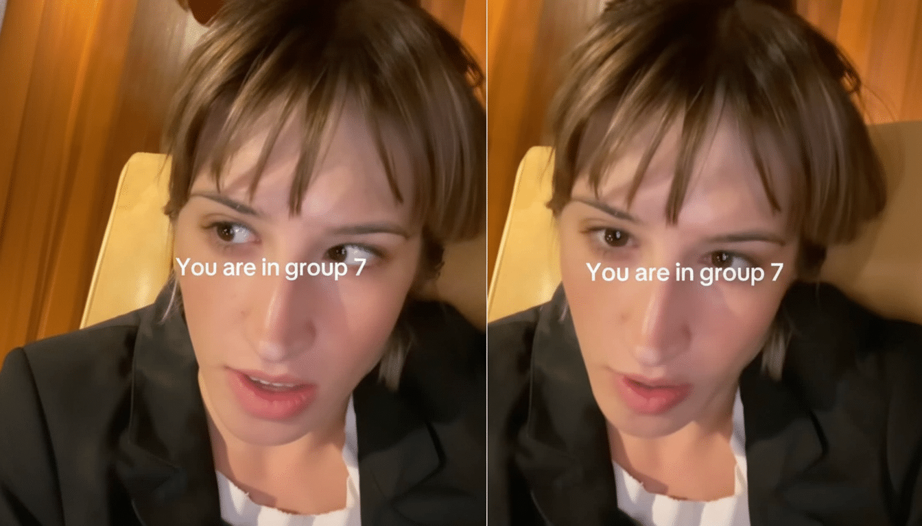 A young woman with short brown hair and bangs , wearing a dark blazer over a white top , looking slightly to the side. The text You are in group 7 is overlaid on the image.