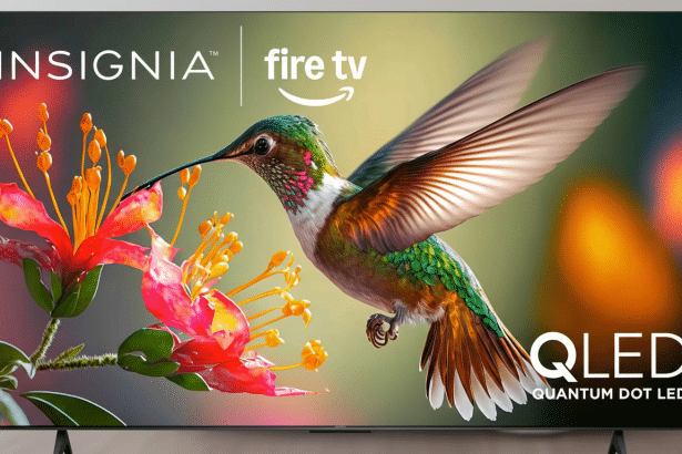 An Ins ignia Fire TV QLED television displaying a vibrant image of a hummingbird next to red and yellow flowers.