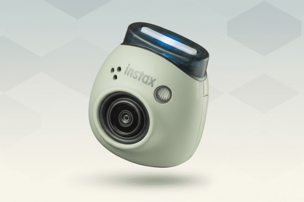 An Instax camera with a light green body and a dark, translucent top with a blue light, floating above a professional flat design background with soft