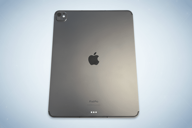 An enhanced, professional image of a Space Gray iPad Pro ( back view ) on a soft, light blue gradient background with subtle geometric patterns.