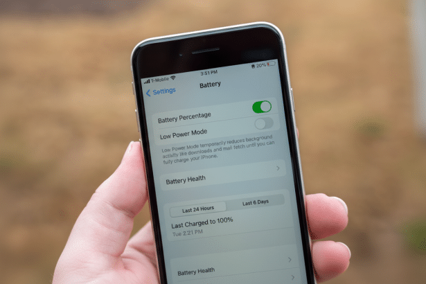 ** A hand holding an iPhone displaying the Battery settings screen with Battery Percentage enabled and Low Power Mode disabled. **