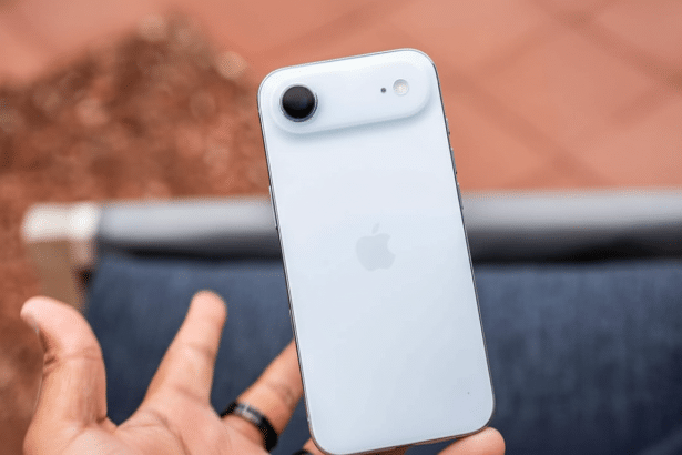 Close -up of a hand holding a white iPhone, showing the back of the phone with the camera and Apple logo.