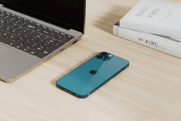 A professional overhead shot of a blue iPhone and a laptop on a wooden desk , with two white books stacked in the background.