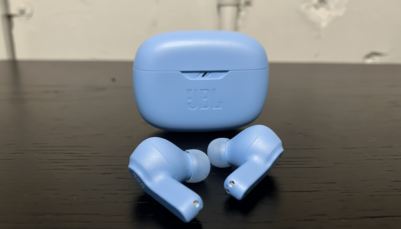 Light blue JBL wireless earbuds and their charging case are displayed on a dark surface .