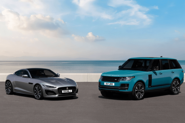 A silver Jaguar F-Type coupe and a teal Range Rover SUV parked side-by -side on asphalt with an ocean and sky background.
