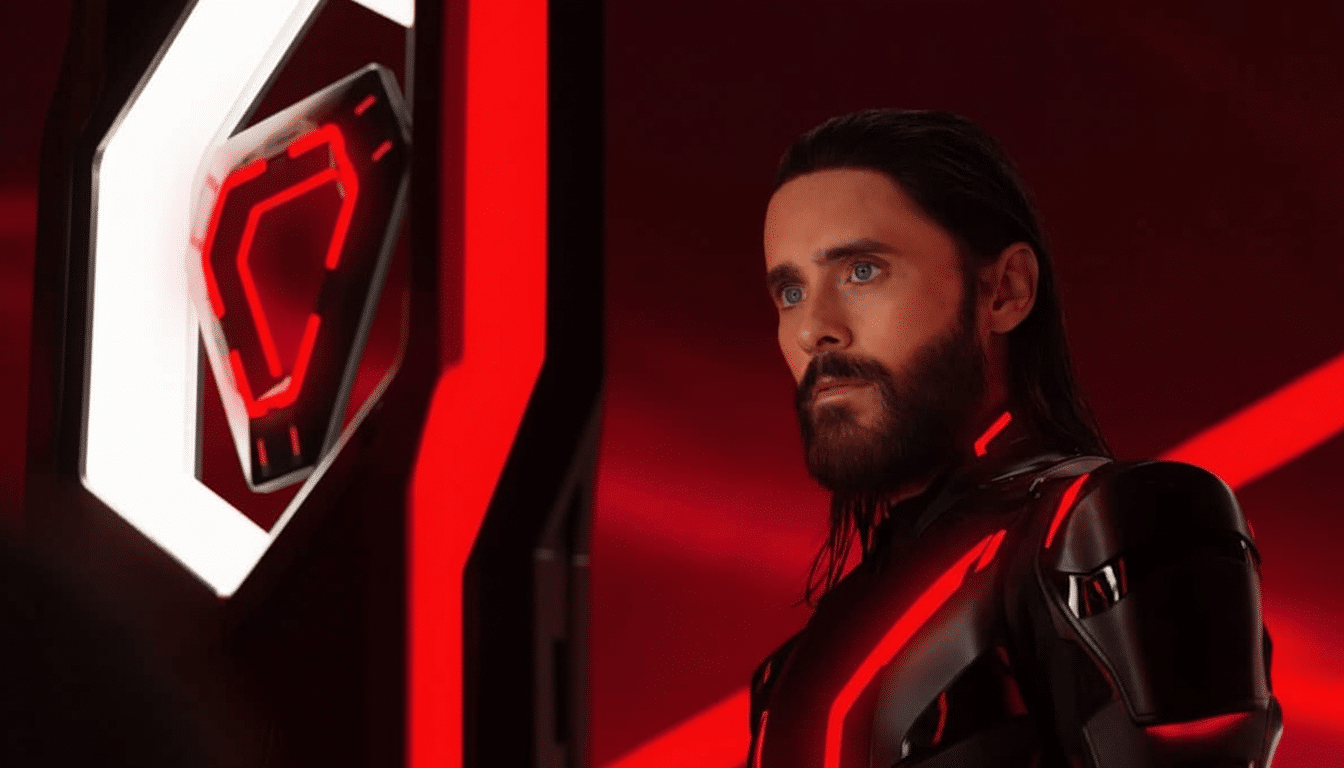 Jared Let o as a character with long hair and a beard, wearing a black suit with red glowing lines, standing in a red- lit futuristic environment.