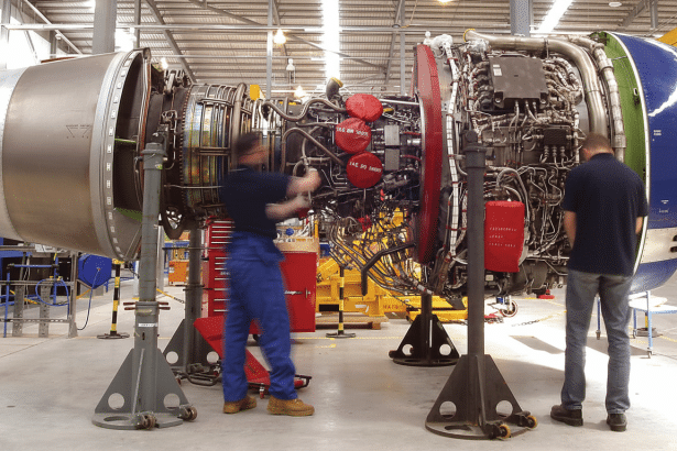 Two engineers working on a large jet engine in a workshop, showcasing the internal components.