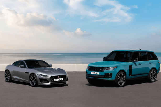 A silver Jaguar F- Type coupe and a teal Range Rover SUV parked side-by- side on an asphalt road with the ocean and a partly cloudy sky in the backgro