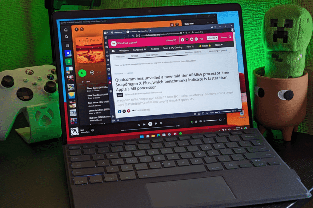 A professional shot of a laptop displaying a news article about a new mid -tier ARM6 4 processor, with a gaming controller and a potted plant in the b