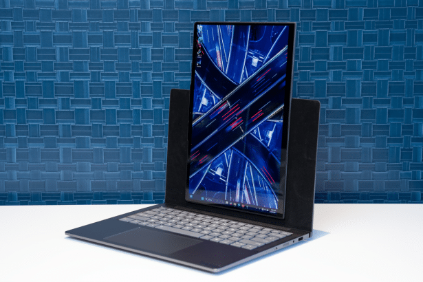 A professional shot of a laptop with its screen upright, displaying a nighttime aerial view of a city intersection. The laptop is set against a textur