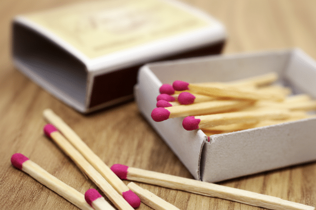 Close -up of an open matchbox filled with matches, with several loose matches scattered on a wooden surface, set at a 1 6:9 aspect ratio. Filename : matches on wood 169 .png